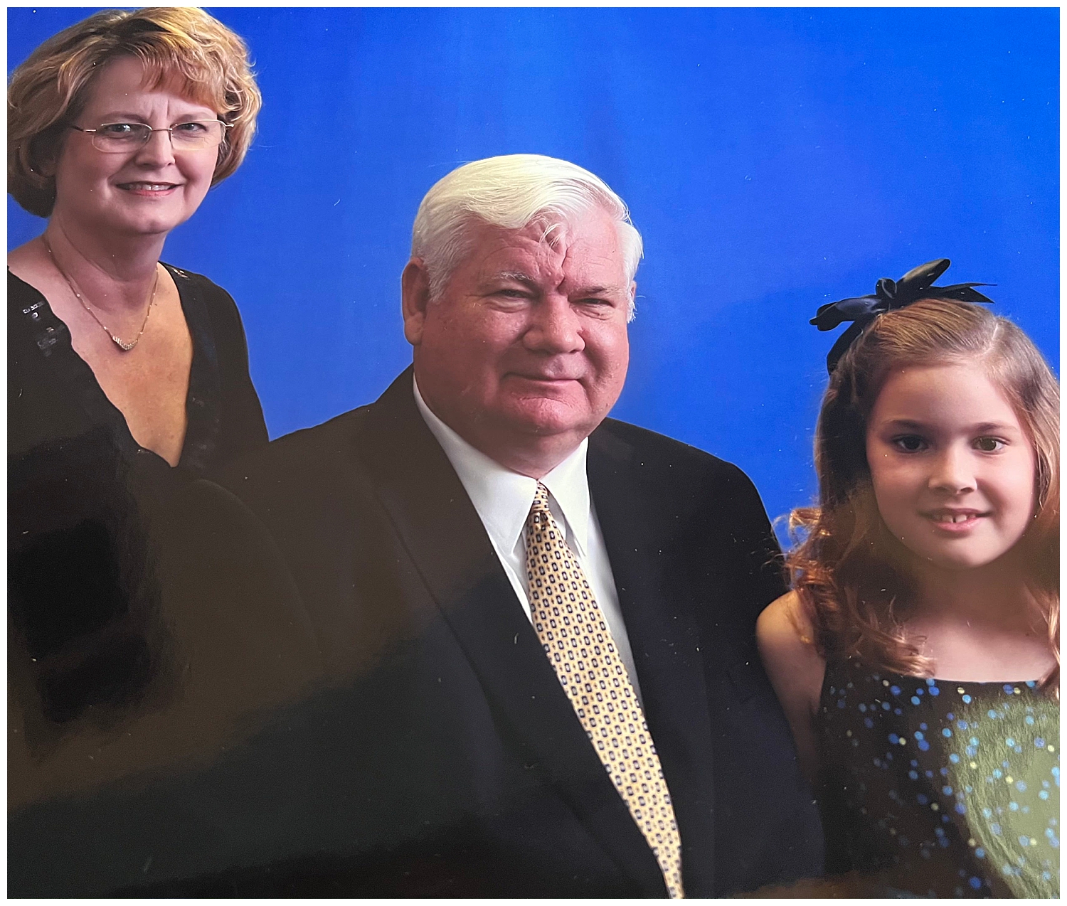 A family smiles at the camera in front of a royal blue wall in Mississippi.