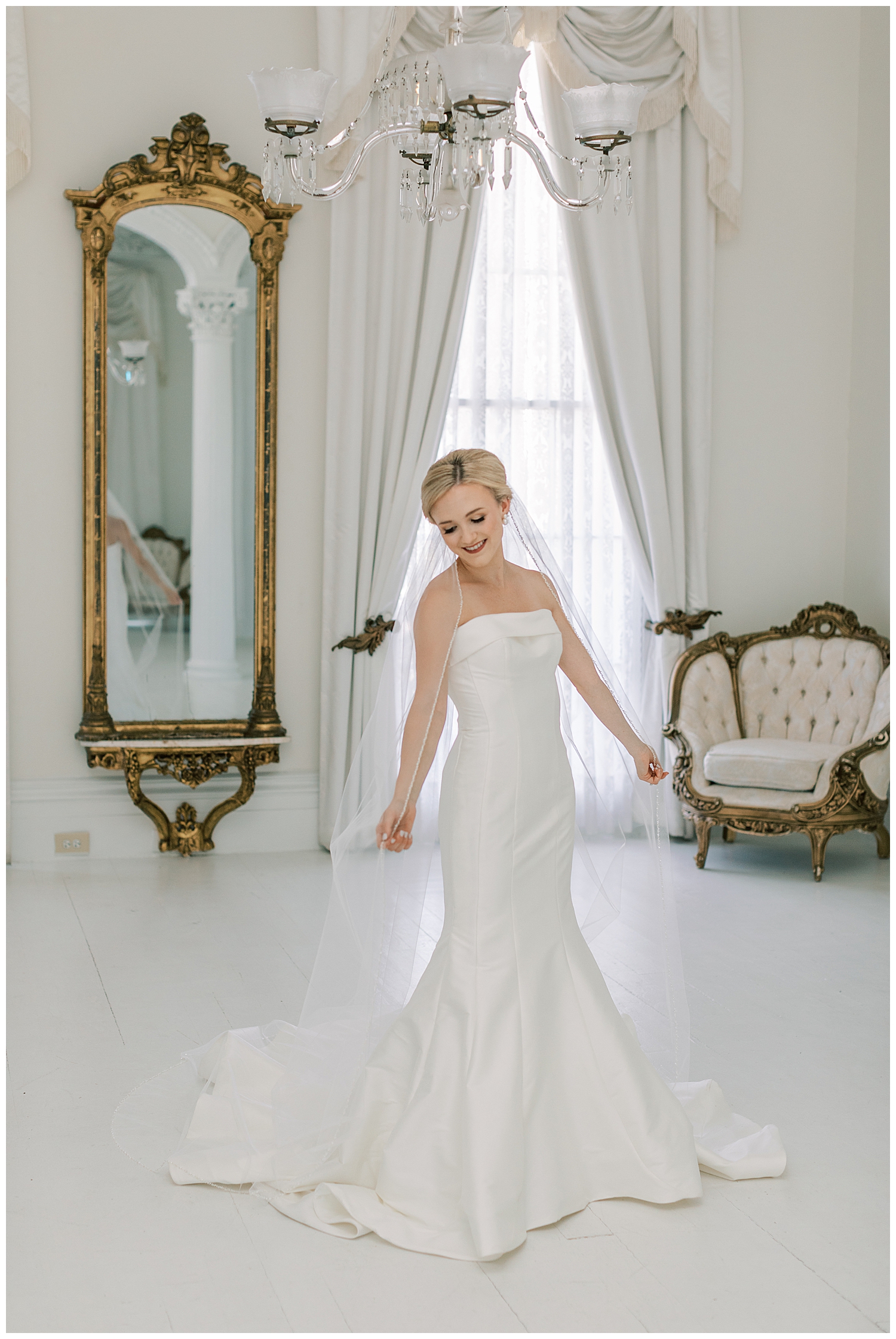 A bride twirls the veil in a white room.