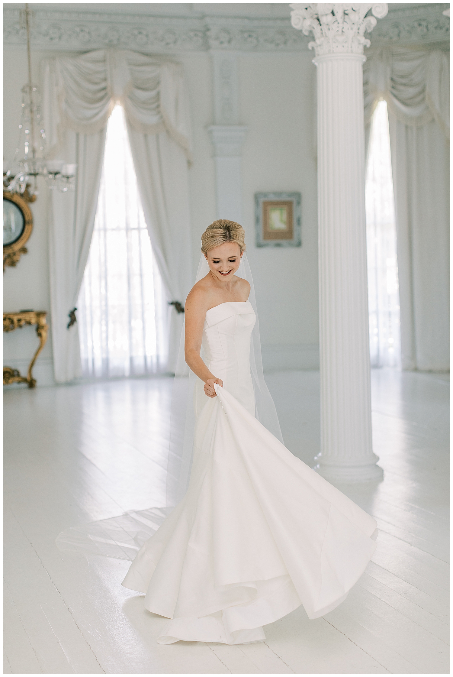 A bride twirls her dress in a white room.