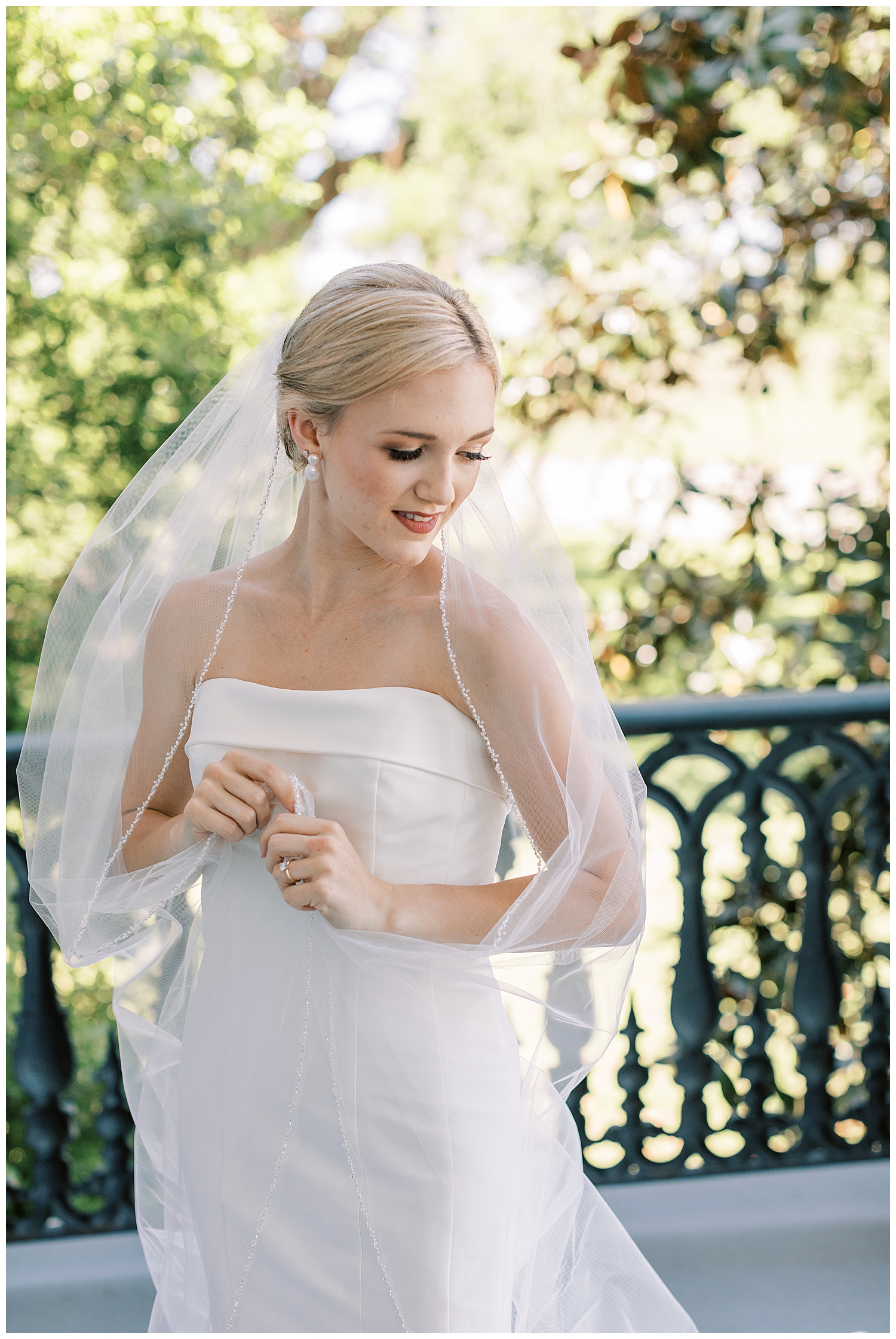 A bride places the veil over her shoulders.