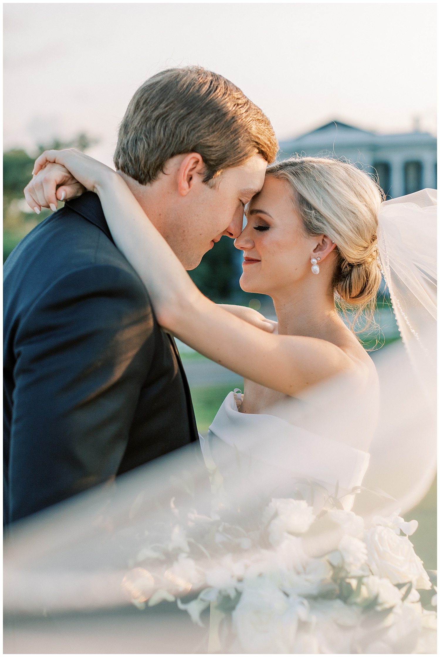 A husband and wife embrace each other with the veil swooping before them.