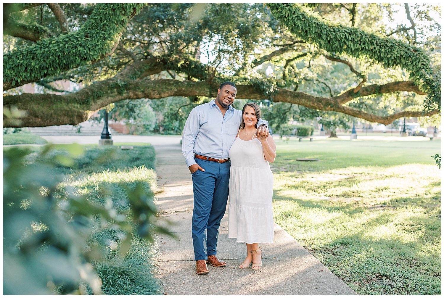 An engaged couple smiles at the camera on the campus of Southern Mississippi University.