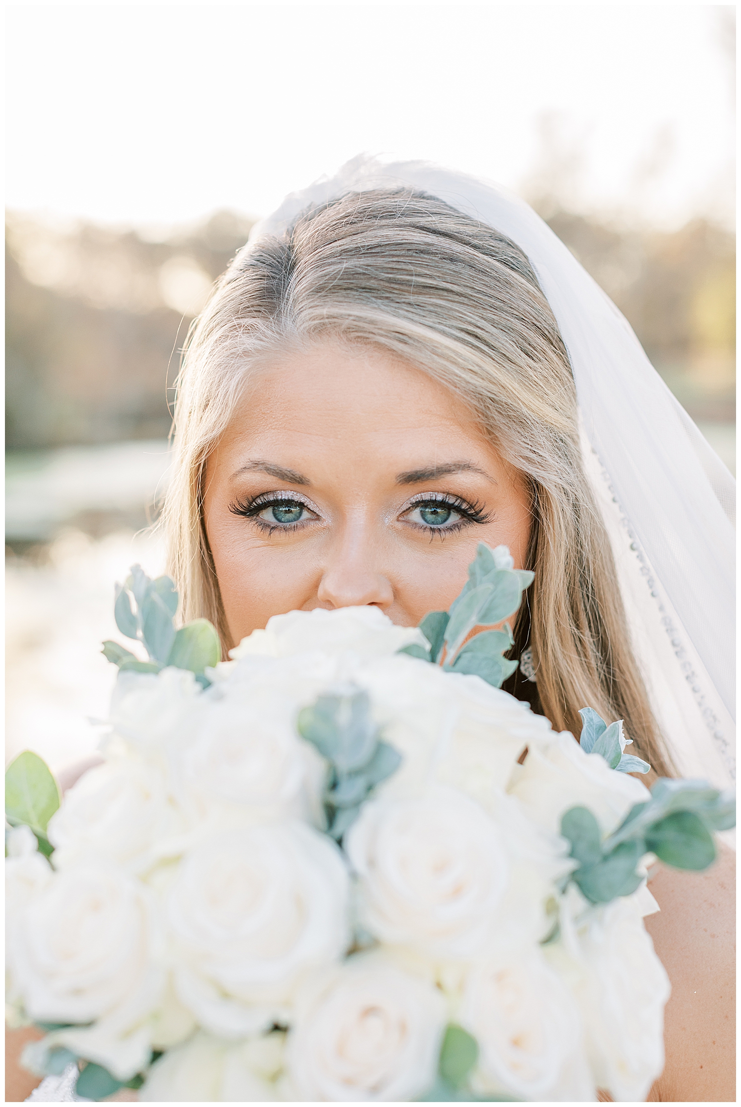 A bride covers her face with her bouquet.