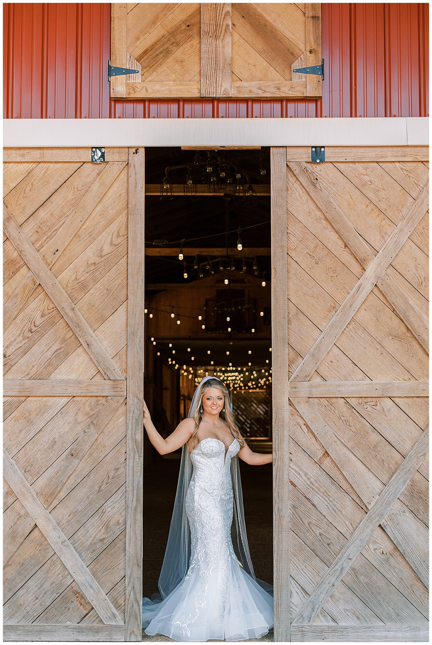 A bride stands between the barn doors.