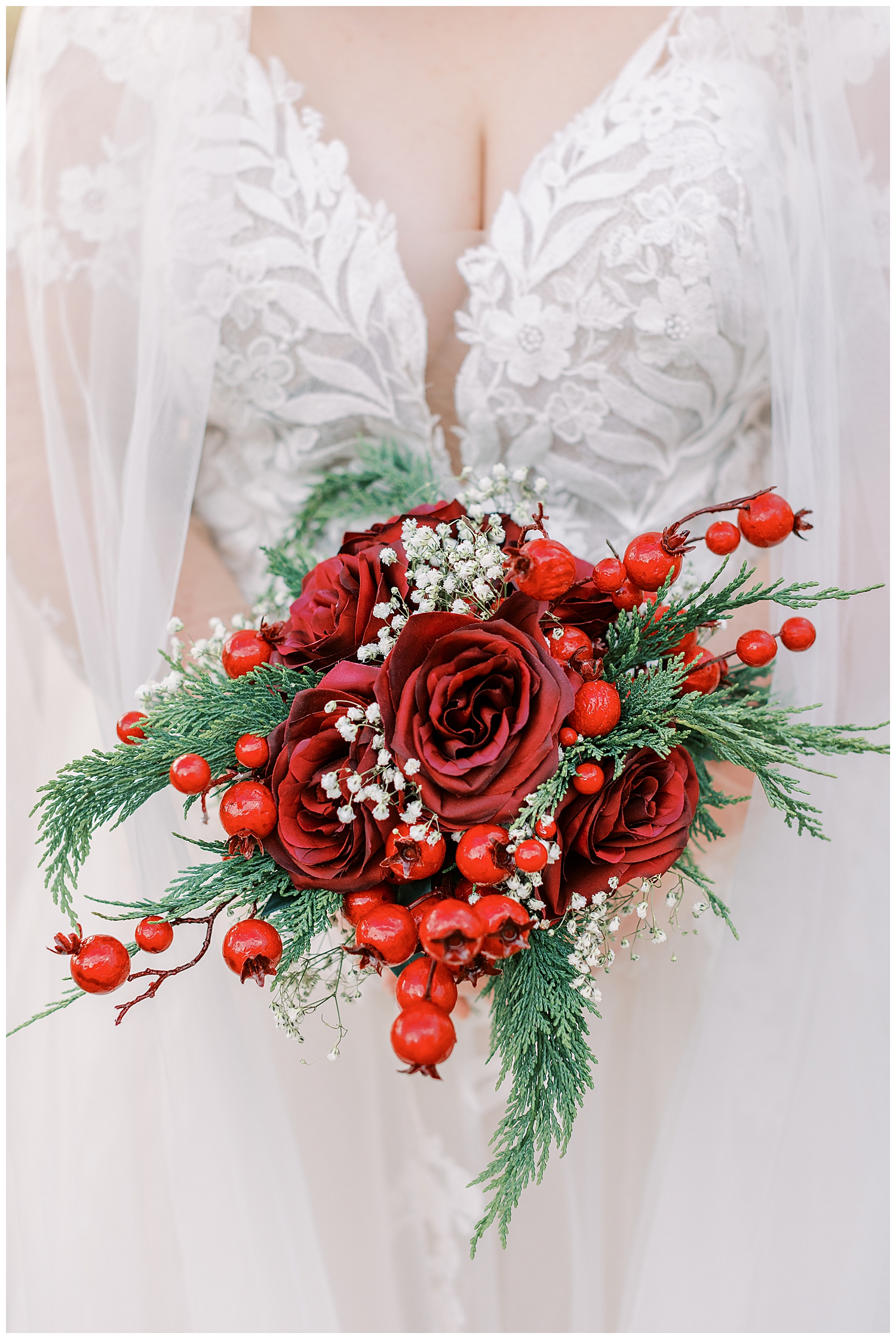 A red and green floral bouquet is held by the bride.