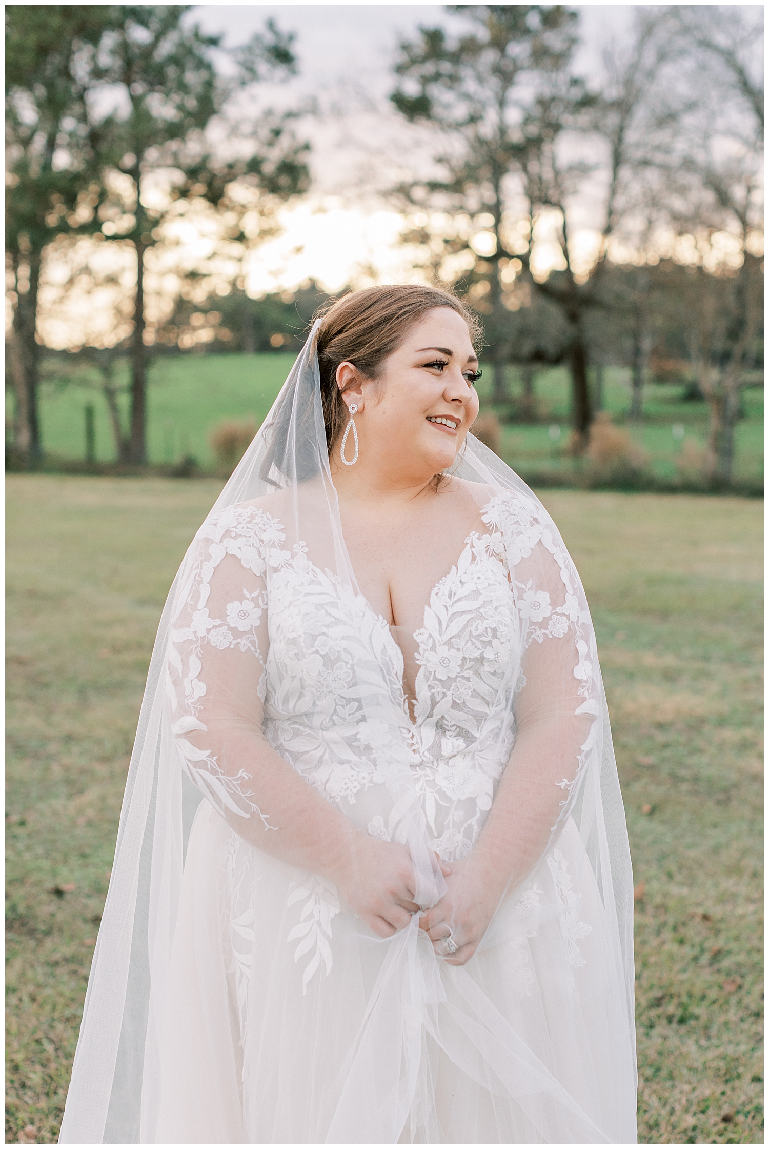 A bride laughs while standing in a field.