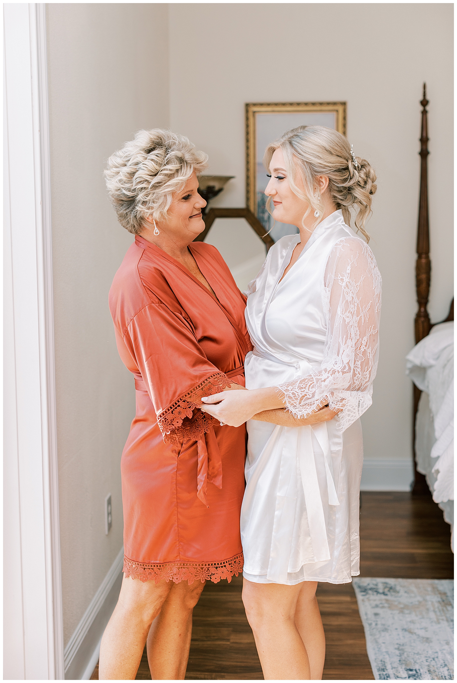 A bride and her mom smile at each other.