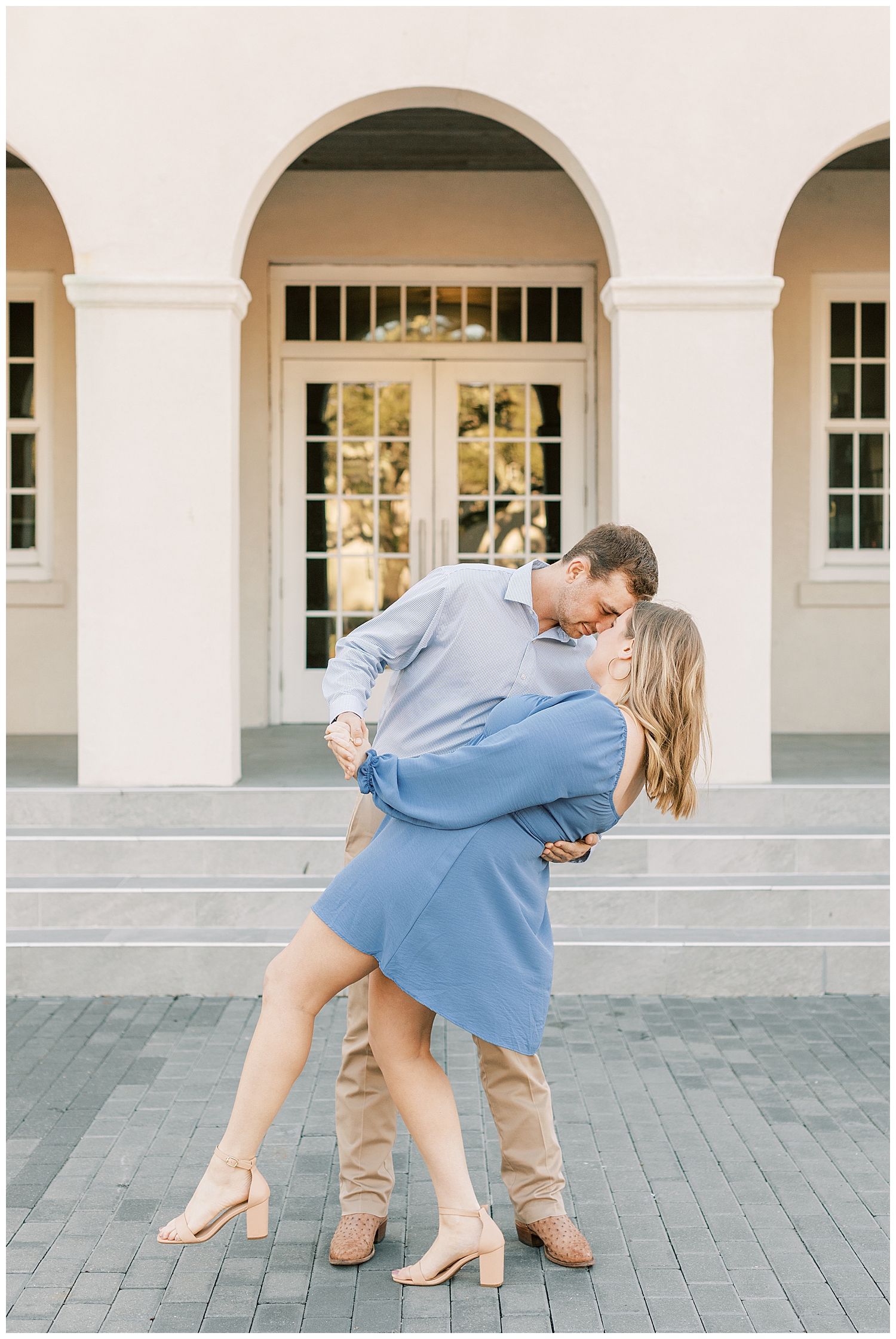 A couple embraces each other in front of an arch.
