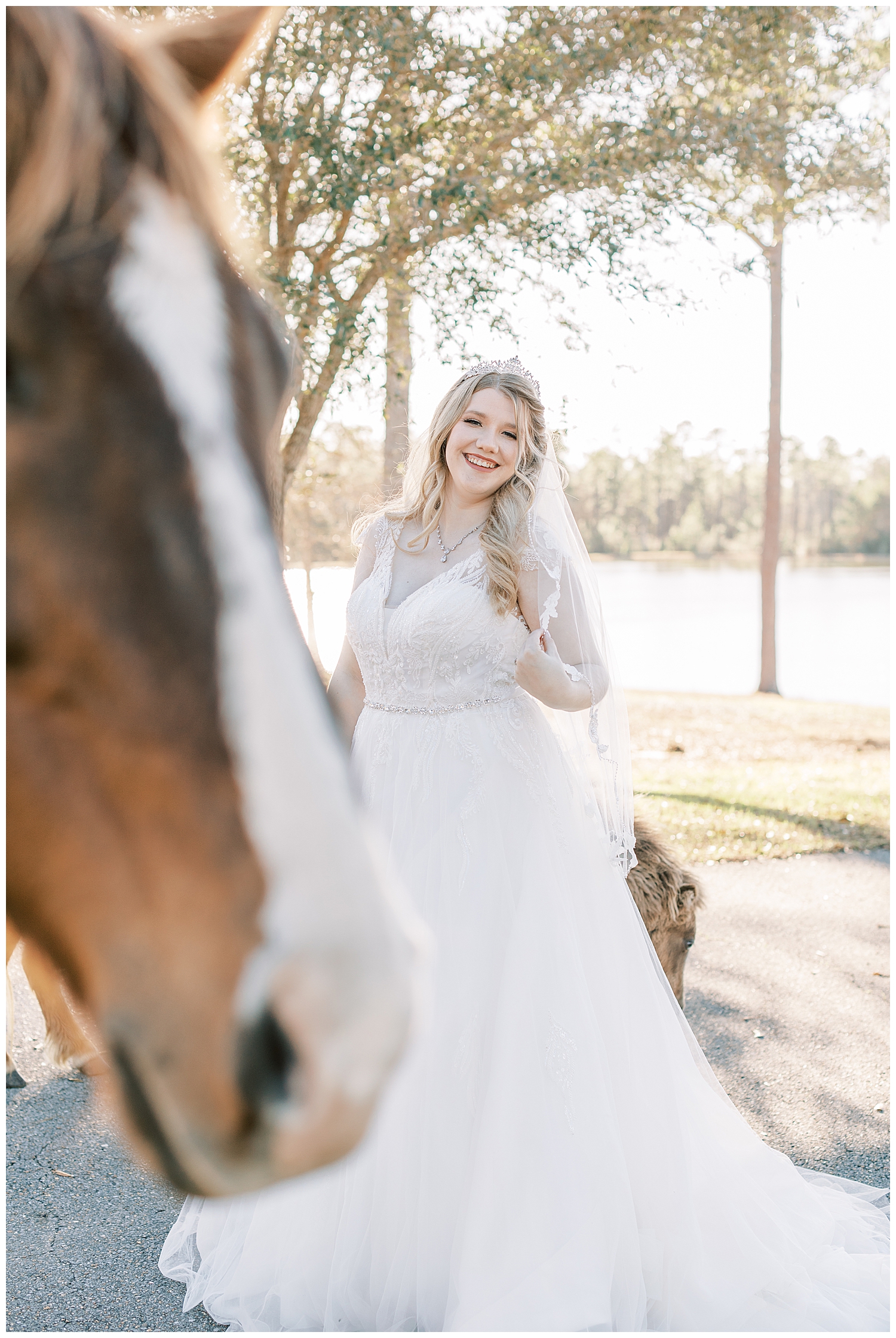 A bride smiles behind a horse.