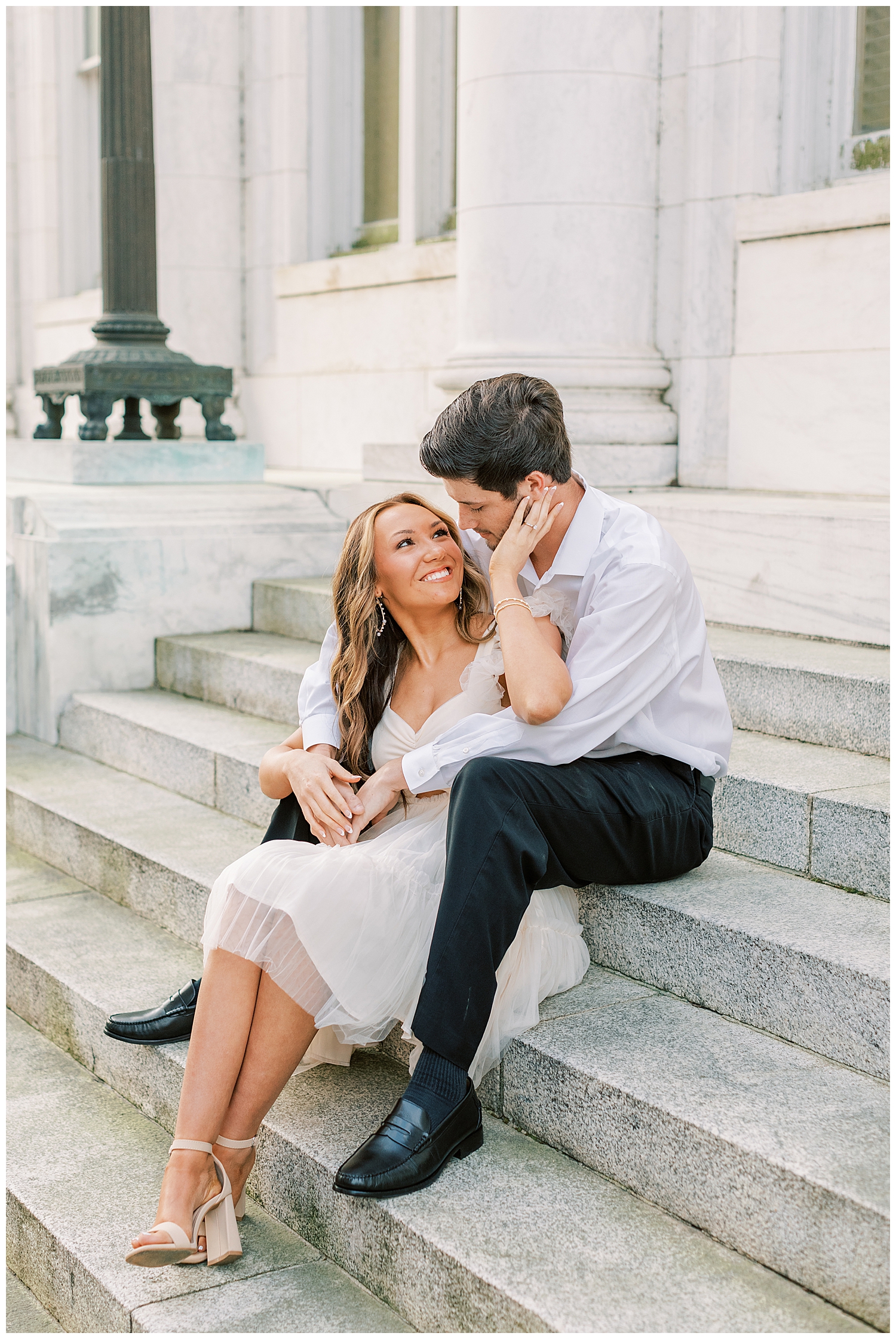 A couple sits on the steps for their spring engagement photos.