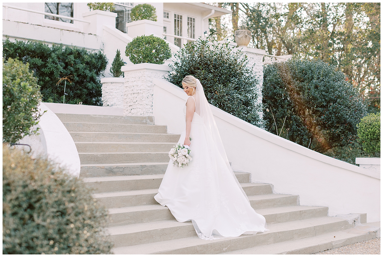 A bride looks down while standing on the steps at The Crawford House.
