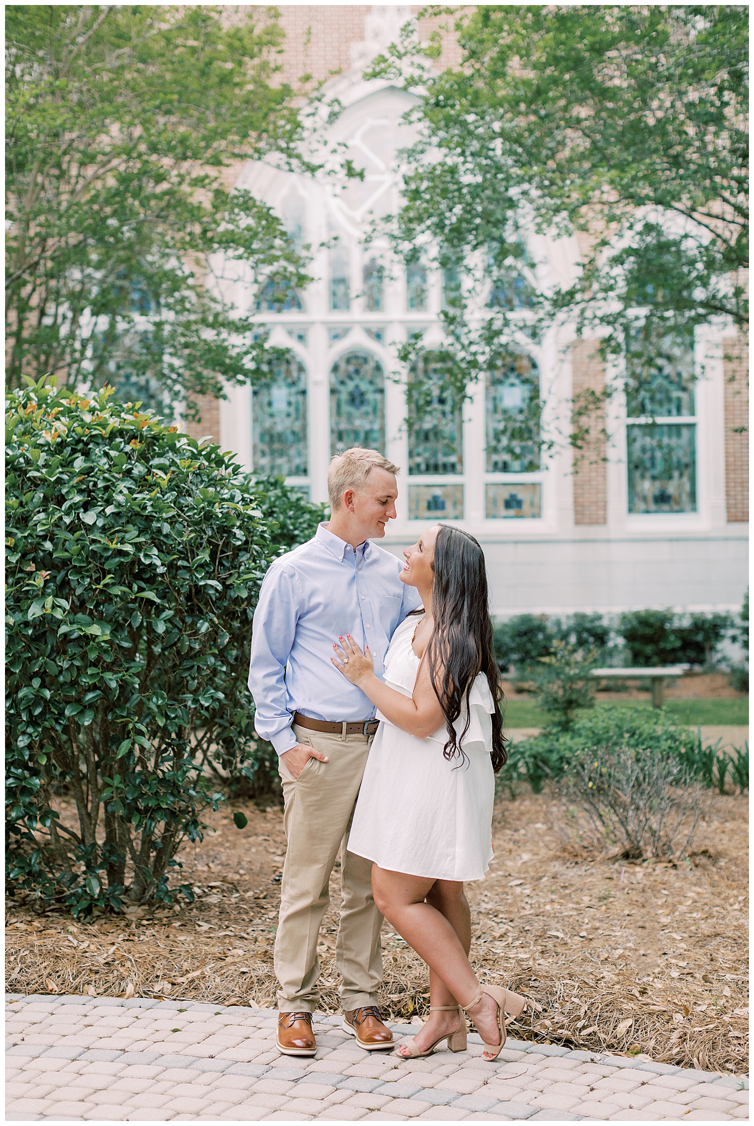 A couple stands in front of stained glass.