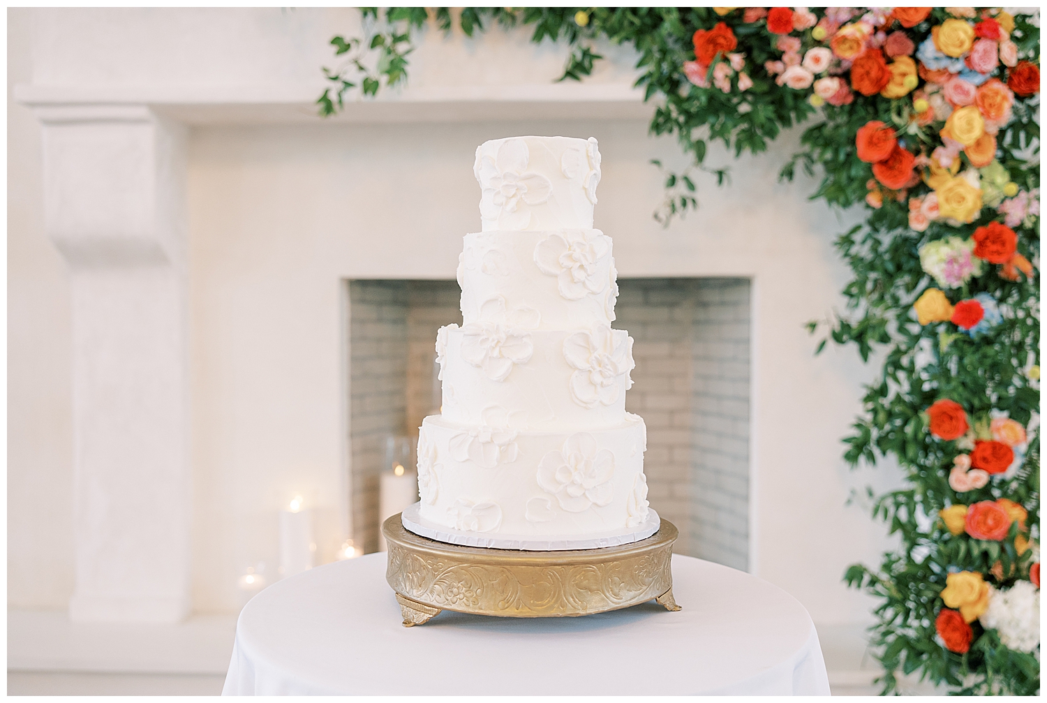 A cake sits in front of a floral arch.