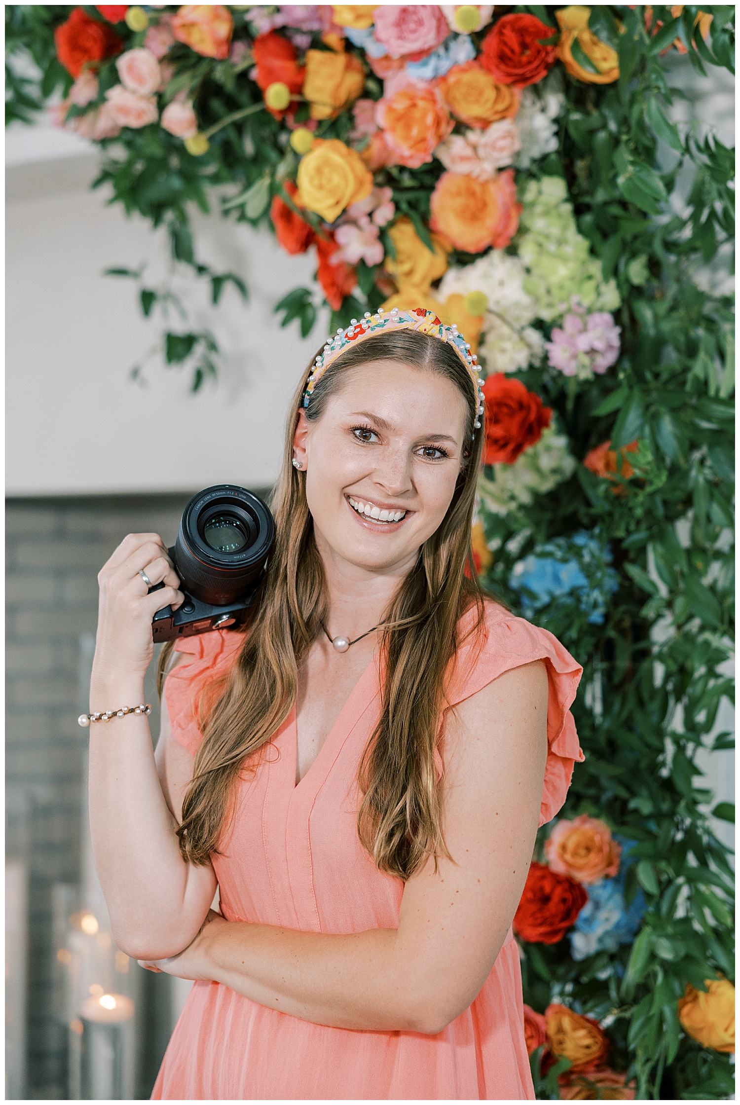 Juliann Riggs smiles for a headshot in front of a floral arch.