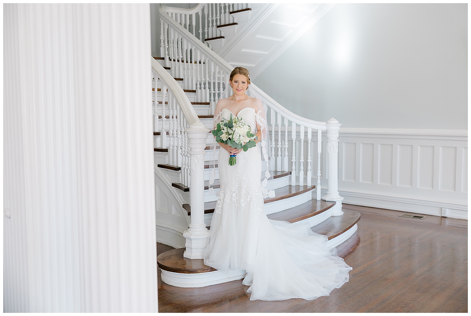 A bride stands on the staircase at Butterfield Mansion while holding her bouquet.